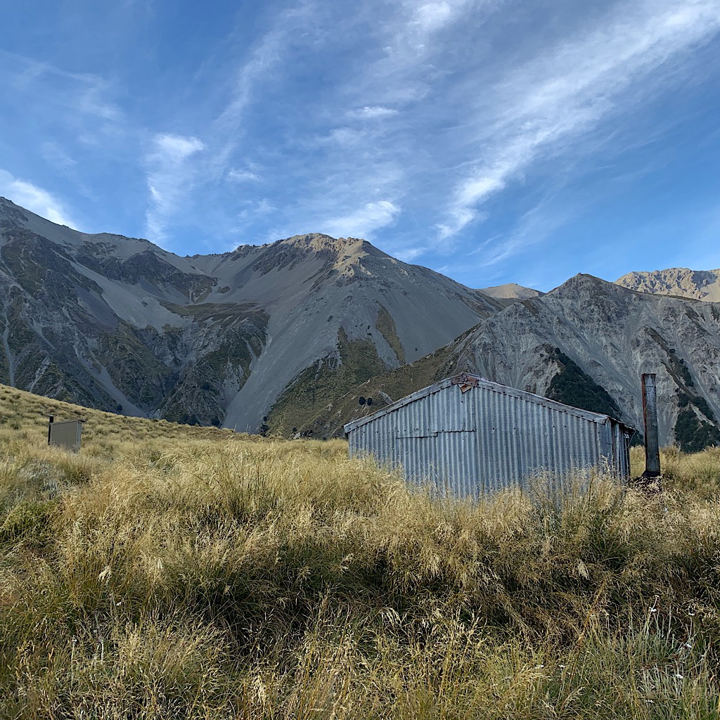 Crooked Spur Hut nestled in surrounded by massive, eroding peaks. 
