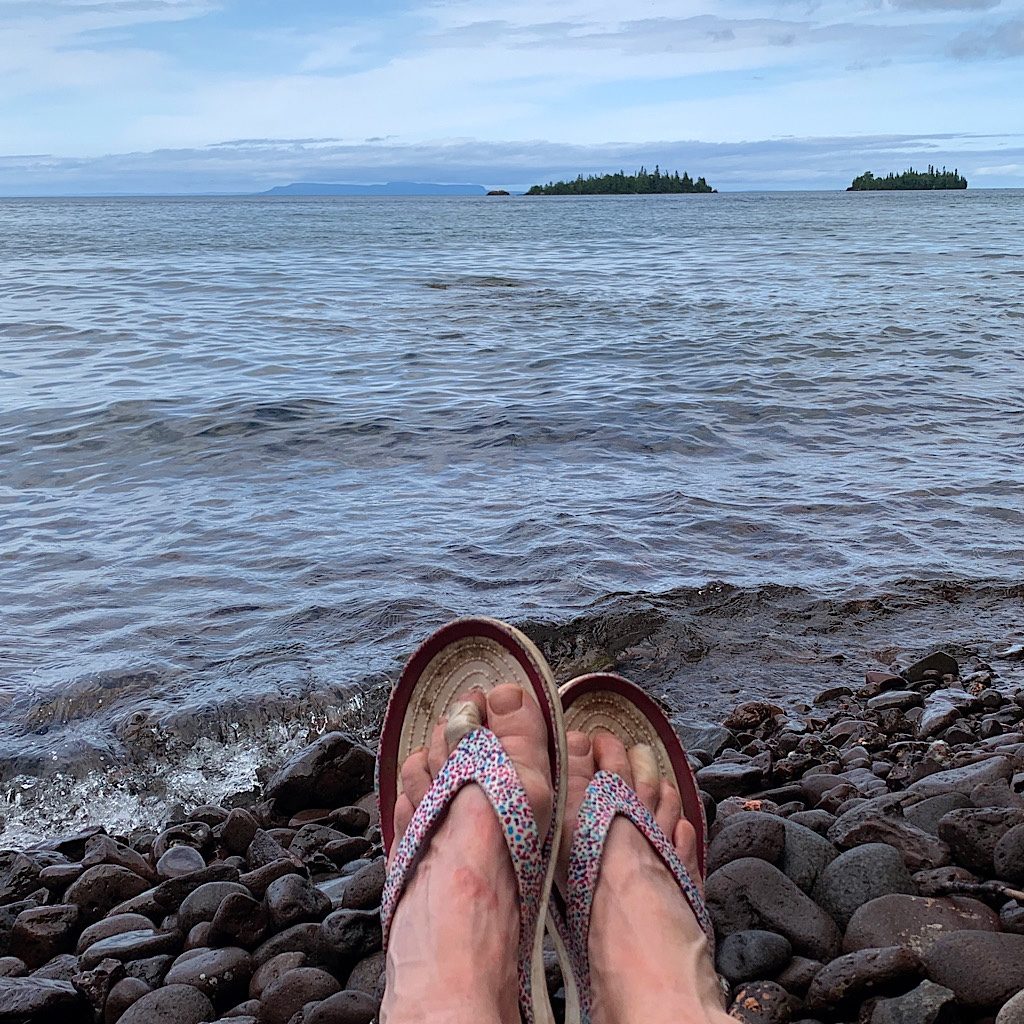 My beat up hiker's feet on a private rocky beach looking towards the Sleeping Giant.